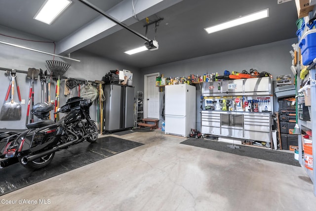 garage with freestanding refrigerator, a workshop area, and a garage door opener