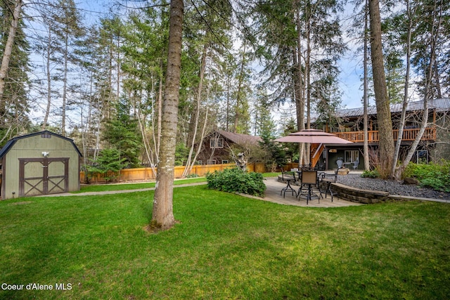 view of yard featuring a patio, a storage unit, fence, a wooden deck, and an outbuilding