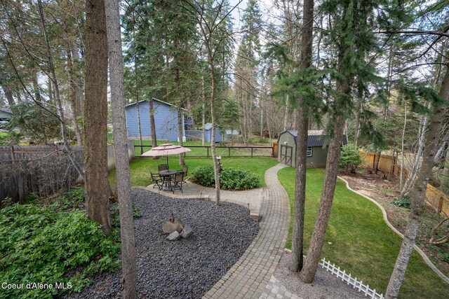 view of yard featuring an outdoor structure, a patio area, a shed, and a fenced backyard