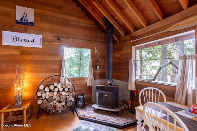 interior space with a wood stove, wooden walls, and lofted ceiling