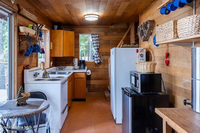 kitchen featuring wood ceiling, a sink, white electric range oven, stainless steel microwave, and wooden walls