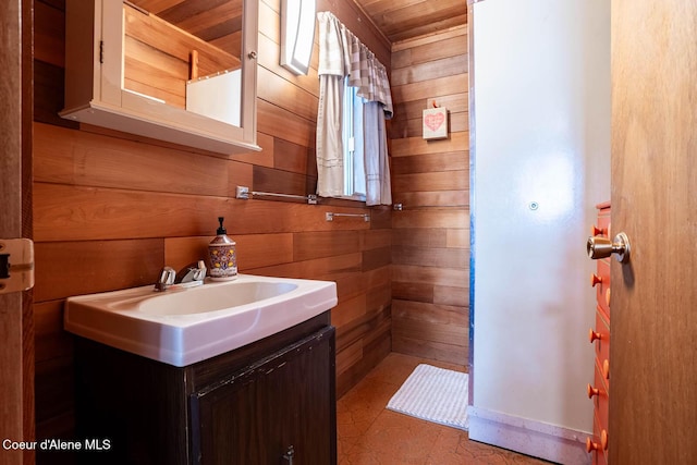 bathroom featuring wood ceiling, wood walls, baseboards, and vanity