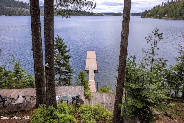 dock area featuring a water view, a wooded view, and fence