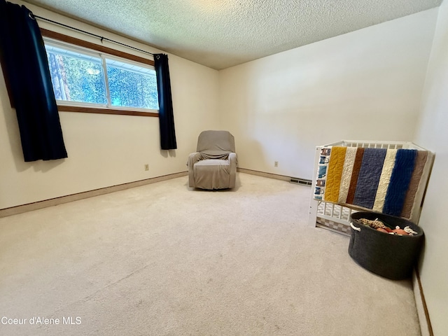 sitting room with carpet floors, baseboards, a textured ceiling, and visible vents