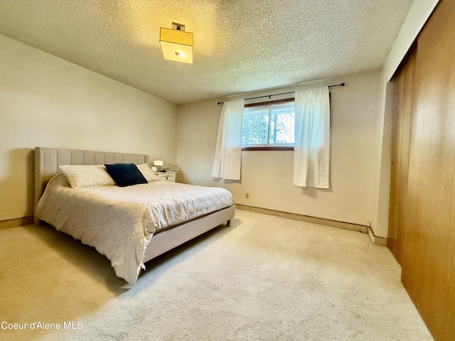 bedroom with a closet, a textured ceiling, carpet, and baseboards