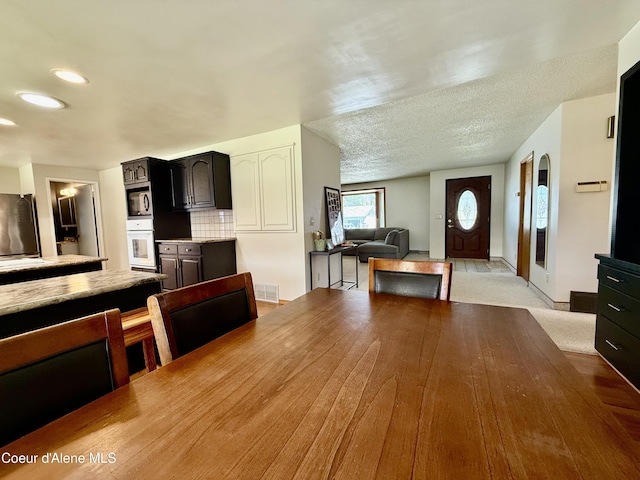interior space with oven, light countertops, built in microwave, recessed lighting, and visible vents