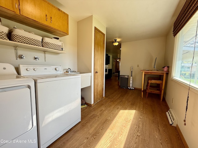 laundry area featuring light wood-type flooring, cabinet space, baseboards, and washing machine and clothes dryer