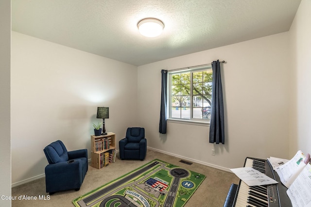 rec room with carpet flooring, a textured ceiling, baseboards, and visible vents