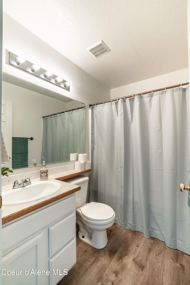 bathroom featuring visible vents, wood finished floors, toilet, and vanity