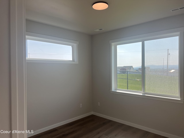 unfurnished room featuring baseboards, visible vents, and dark wood-style floors