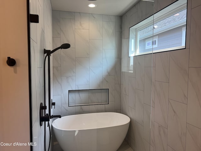 full bathroom with a freestanding tub and tile walls
