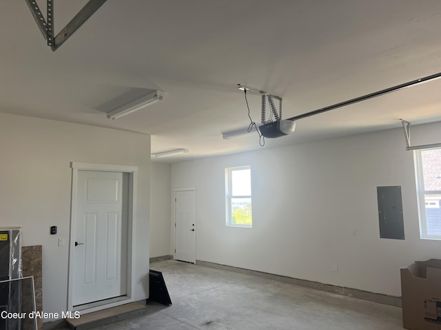 garage featuring baseboards, a garage door opener, and electric panel