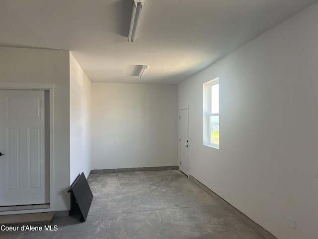 corridor with baseboards and unfinished concrete flooring