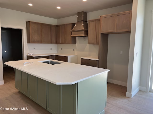 3397 N Blaze Loop, Post Falls, ID 83854 - kitchen with baseboards, recessed lighting, an island with sink, premium range hood, and light wood-style flooring