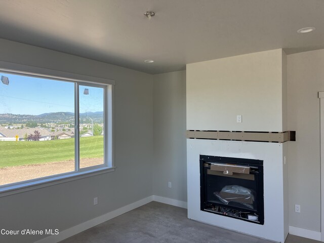 3397 N Blaze Loop, Post Falls, ID 83854 - unfurnished living room with a glass covered fireplace, finished concrete flooring, baseboards, and a mountain view