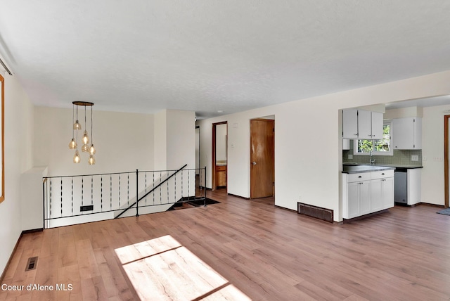 407 E Buttercup Ln, Coeur Dalene, ID 83815 - unfurnished living room featuring visible vents, a sink, baseboards, and light wood-type flooring