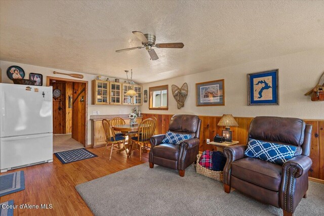 34128 N Scenic Bay D Dock Unit 21, Bayview, ID 83803 - living area featuring a textured ceiling, wood walls, a wainscoted wall, a ceiling fan, and wood finished floors