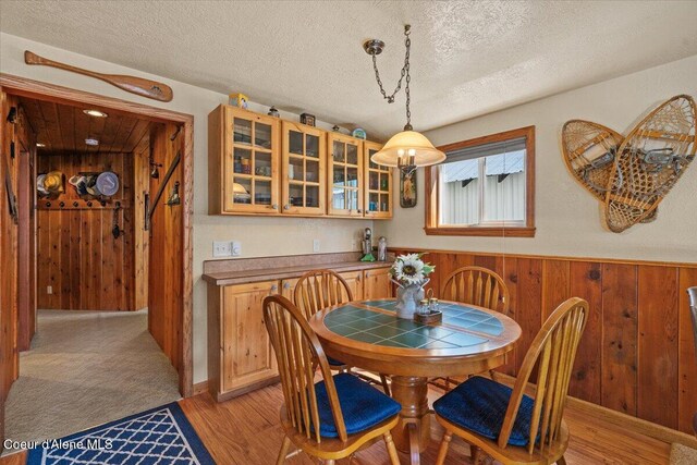 34128 N Scenic Bay D Dock Unit 21, Bayview, ID 83803 - dining space with wooden walls, a textured ceiling, light wood finished floors, and a wainscoted wall