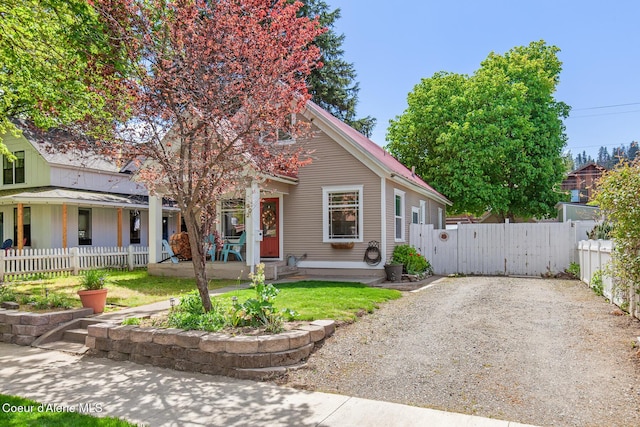 view of front of house with covered porch, a gate, fence, and gravel driveway
