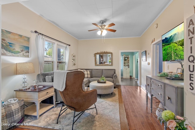 living area with a ceiling fan, baseboards, crown molding, and wood finished floors