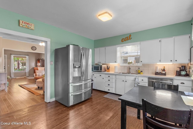 kitchen with stainless steel appliances, white cabinets, a sink, and wood finished floors