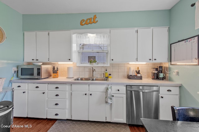 kitchen with a sink, stainless steel appliances, decorative backsplash, and dark wood finished floors