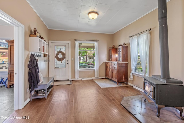 entryway featuring a wood stove, crown molding, baseboards, and hardwood / wood-style floors