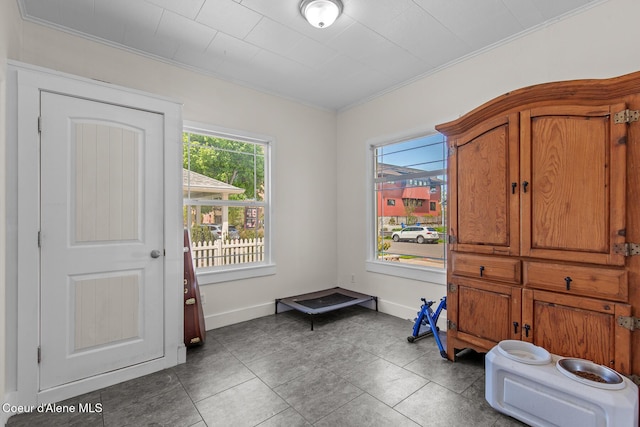 interior space with crown molding, baseboards, and tile patterned flooring