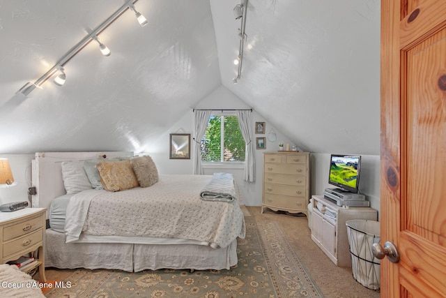 bedroom featuring lofted ceiling, carpet, and track lighting