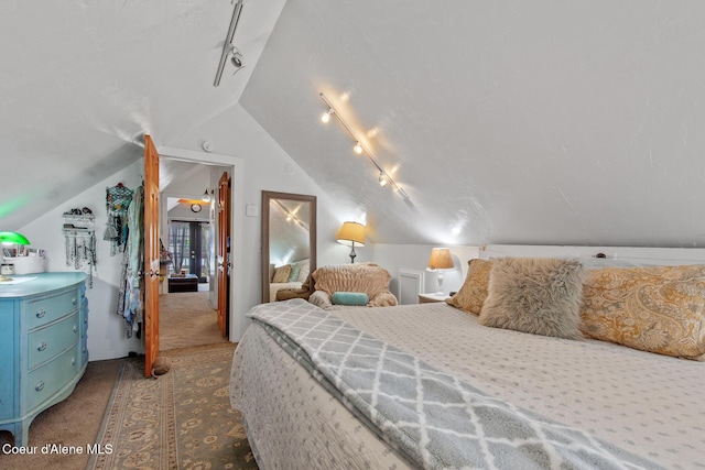 carpeted bedroom with rail lighting and lofted ceiling