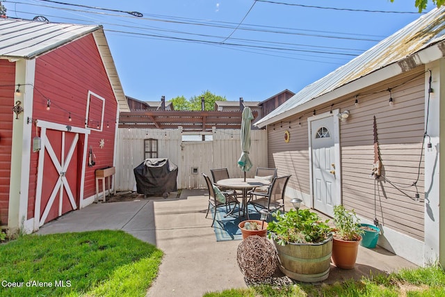 view of patio / terrace with an outdoor structure, fence, and outdoor dining space