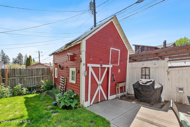 view of barn featuring fence and a lawn