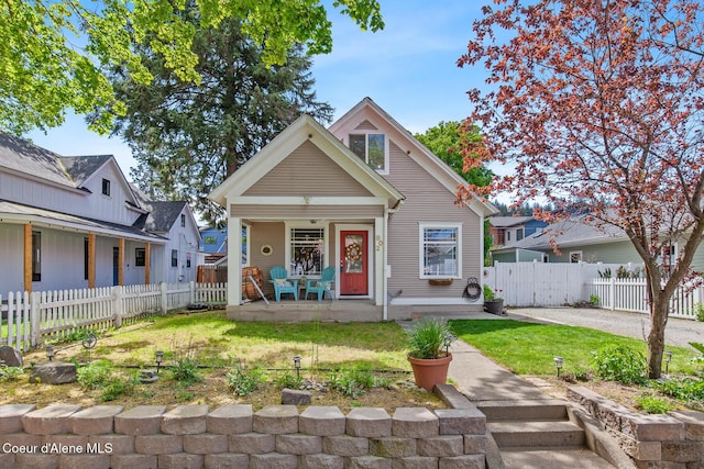 bungalow-style home featuring covered porch, fence, and a front lawn