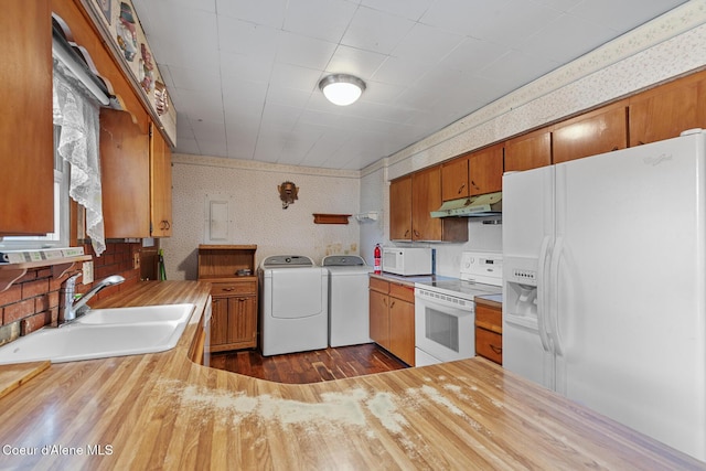 17871 N Ramsey Rd, Rathdrum, ID 83858 - kitchen with white appliances, washer and dryer, under cabinet range hood, brown cabinets, and dark wood finished floors