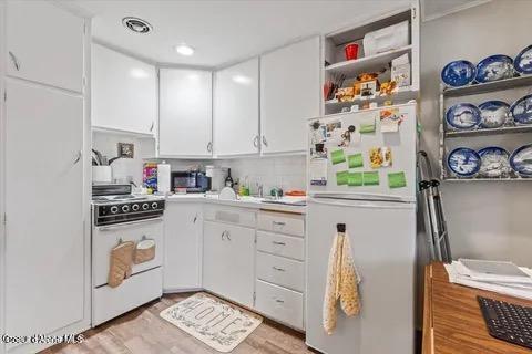 712 E Coeur D Alene Ave, Coeur Dalene, ID 83814 - kitchen featuring open shelves, white cabinetry, white appliances, light countertops, and light wood-style floors