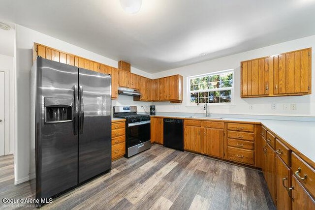 1547 E Stratford Dr, Hayden, ID 83835 - kitchen with brown cabinets, a sink, stainless steel appliances, under cabinet range hood, and dark wood-style floors