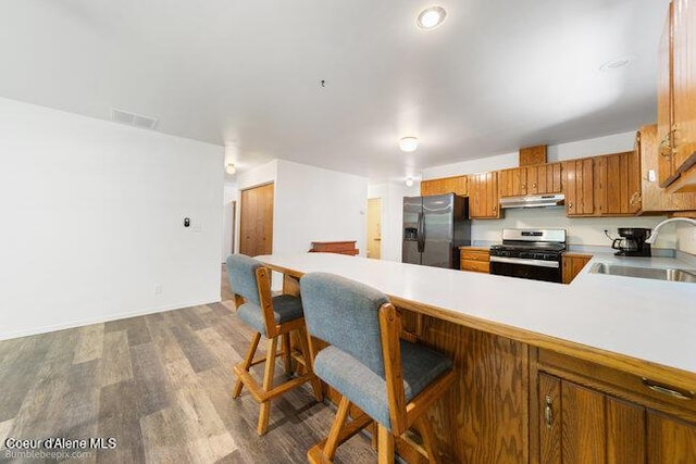 1547 E Stratford Dr, Hayden, ID 83835 - kitchen featuring a sink, stainless steel appliances, brown cabinetry, visible vents, and under cabinet range hood