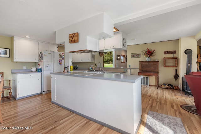 kitchen featuring light wood finished floors, white cabinetry, light countertops, stovetop, and white refrigerator with ice dispenser