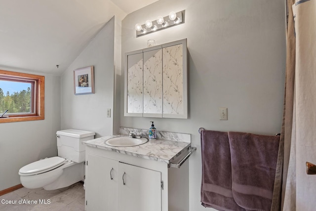 bathroom featuring toilet, vaulted ceiling, and vanity