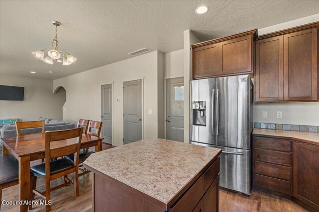 2097 W Calawah Ave, Post Falls, ID 83854 - kitchen featuring stainless steel fridge, arched walkways, wood finished floors, a chandelier, and a textured ceiling