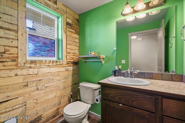 2097 W Calawah Ave, Post Falls, ID 83854 - half bathroom featuring wood walls, toilet, and vanity