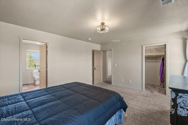 2097 W Calawah Ave, Post Falls, ID 83854 - bedroom with light colored carpet, a textured ceiling, a walk in closet, baseboards, and ensuite bathroom