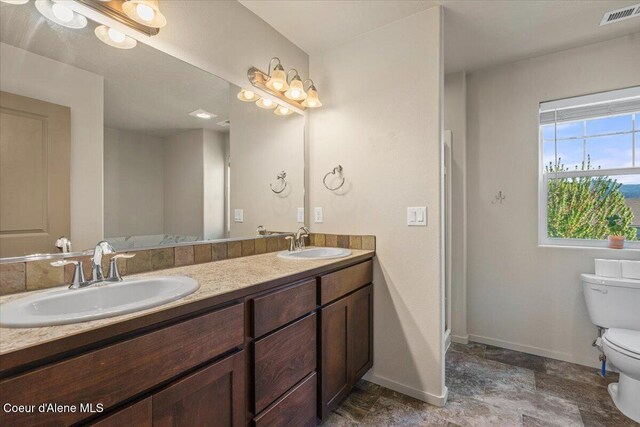 2097 W Calawah Ave, Post Falls, ID 83854 - bathroom featuring toilet, baseboards, double vanity, and stone finish flooring
