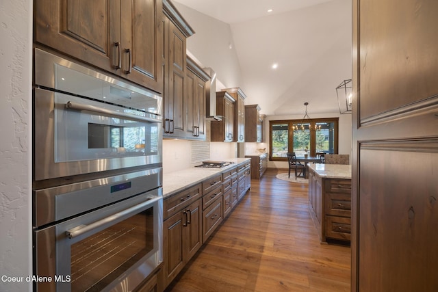 11671 N Spiraea Ln, Hayden, ID 83835 - kitchen with wood finished floors, stainless steel appliances, light stone counters, lofted ceiling, and a chandelier