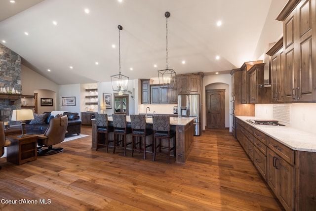 11671 N Spiraea Ln, Hayden, ID 83835 - kitchen featuring arched walkways, stainless steel appliances, dark wood finished floors, a large island, and a breakfast bar