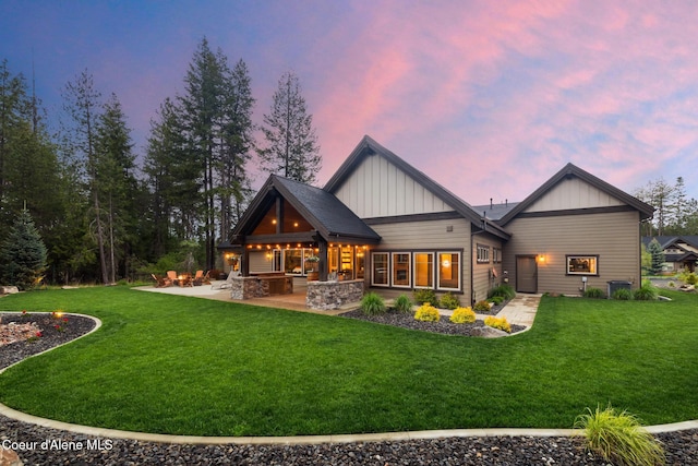 11671 N Spiraea Ln, Hayden, ID 83835 - back of property at dusk with board and batten siding, a patio, and a yard