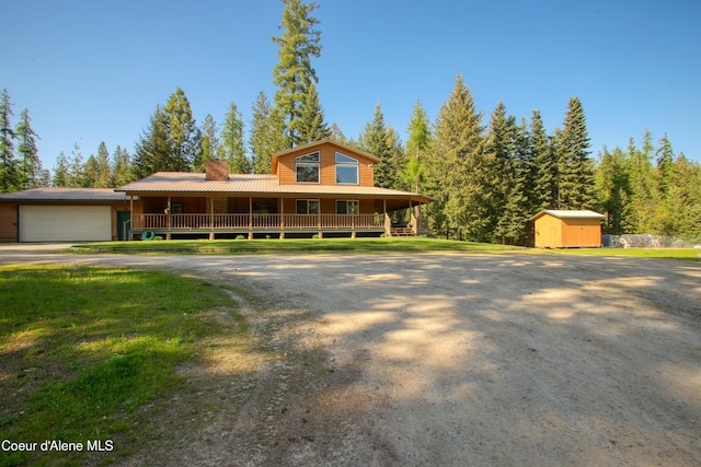 31582 E Hayden Lake Rd, Hayden, ID 83835 - view of front of property featuring a chimney, an outdoor structure, covered porch, an attached garage, and a storage shed