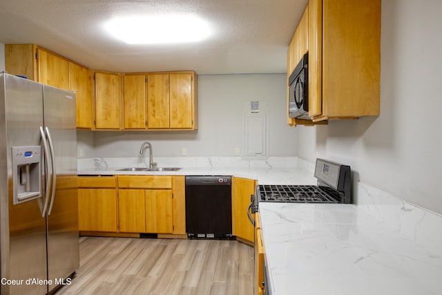 31582 E Hayden Lake Rd, Hayden, ID 83835 - kitchen featuring brown cabinetry, a sink, black appliances, light wood-style floors, and light countertops