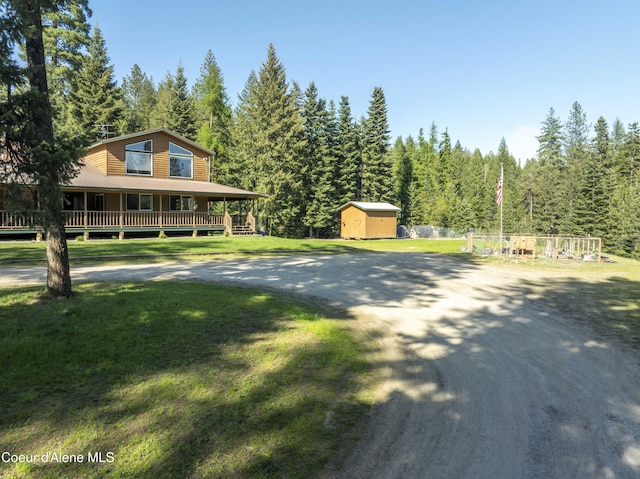 31582 E Hayden Lake Rd, Hayden, ID 83835 - view of front of house featuring a storage shed, an outdoor structure, driveway, a front yard, and a forest view