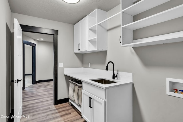 2878 N Callary St, Post Falls, ID 83854 - clothes washing area featuring baseboards, hookup for a washing machine, a sink, light wood-type flooring, and cabinet space